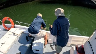 Unidos en la Emoción: La Espera de la Gran Captura - Esta foto muestra a Rainier González padre y Noble Donoso en un intenso momento de camaradería.la tensión y la emoción de la lucha que se libra bajo el agua, su atención centrada en las cañas que se doblan bajo la fuerza de una posible gran captura de Pargo Rojo.