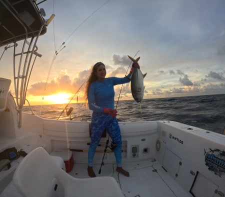 La experta pescadora Mónica López muestra con orgullo su primera captura del día, un robusto Jurel, testimonio de una jornada exitosa de pesca.