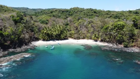 Esta imagen desde el dron captura la serenidad y la paz que se encuentran en Playita. La playa, inmaculada y bañada por el sol, te invita a relajarte y disfrutar de un momento de escapada en medio de la naturaleza. Las suaves olas que se deslizan sobre la arena y la brisa tropical que acaricia tu rostro crean una atmósfera mágica que te transporta a un estado de completa tranquilidad.