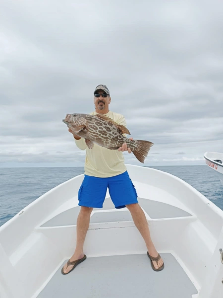 Diversión en Miniatura: Capturando Pequeños Meros en Pesca Cambutal - Sumérgete en la diversión de la pesca deportiva con nuestra foto de un cliente satisfecho mostrando su captura de un pequeño Mero. Aunque pequeño en tamaño, este pez es conocido por su lucha valiente, ofreciendo una experiencia de pesca animada y agradable. La sonrisa de nuestro cliente refleja la alegría de capturar este adorable pez en las aguas de Cambutal.